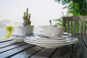 stack of bowl and plates with spoon and fork , after meal, on wooden table