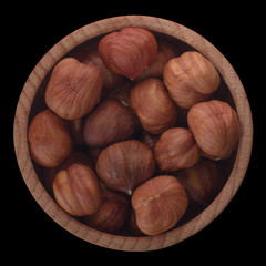 shelled hazelnuts  in wooden cup isolated on black background. top view