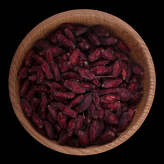 dried red barberries  in wooden cup isolated on black background.  top view