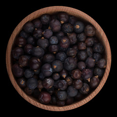 juniper berries in wooden cup isolated on black background. top view