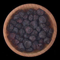 dried blueberry (bilberry)in wooden cup isolated on black background. top view
