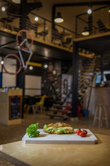 An appetizing sandwich on a wooden board with vegetables.