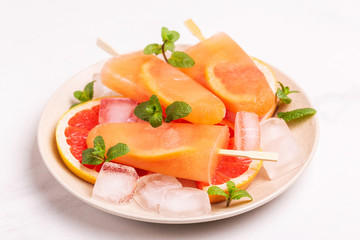 Homemade grapefruit popsicle with ripe grapefruit slices and fresh mint