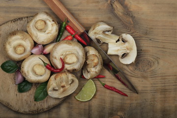 champignons with spices on wooden background