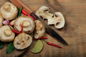 champignons with spices on wooden background