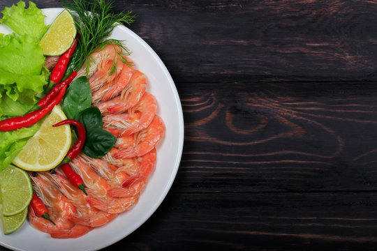 cooced prawns with spices in plate on wooden background. top view