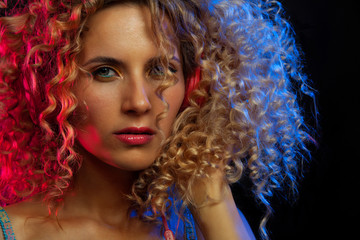 Fototapeta premium Attractive dancing woman with curly hair and red headphones in black background, neon light, motion effects. Copyspace.
