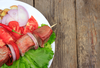 kebab with lettuce and tomatoes on wooden background