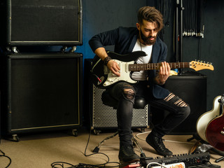 Handsome man playing an electric guitar in a studio