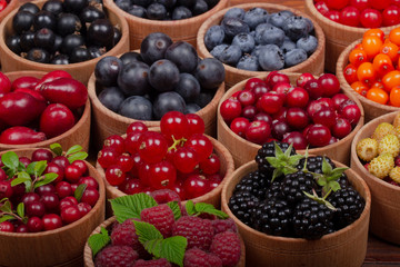 berries in wooden cups on wooden background