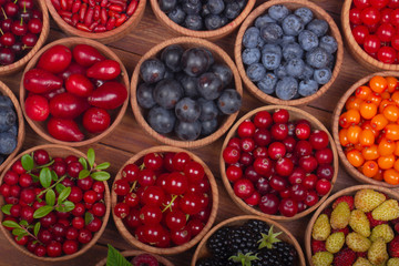berries in wooden cups on wooden background. top view