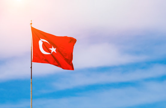 Waving flag of Turkey in sunny blue sky