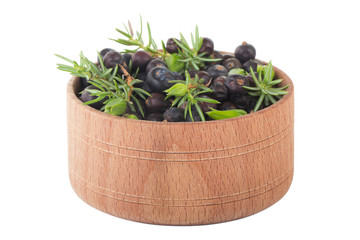 heap of juniper berries in wooden cup isolated on white background