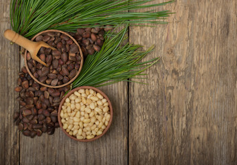 cedar nuts in wooden cups on wooden background