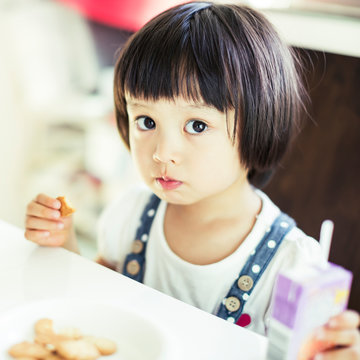テーブルに座りお菓子を食べる女の子