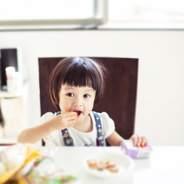 テーブルに座りお菓子を食べる女の子