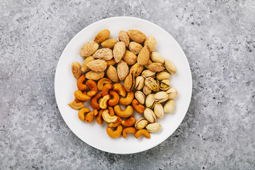 Nuts for beer in a white ceramic plate, top view
