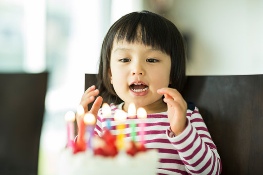 Girl with black hair sitting in front of birthday cake