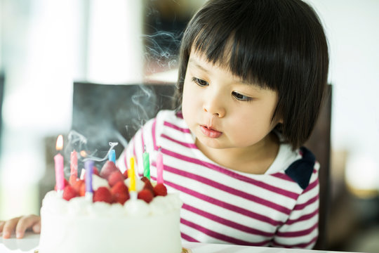 Girl with black hair blowing out candle