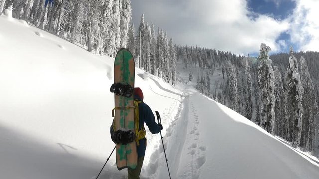 Young male snowboarder walking up on a beautiful winter day