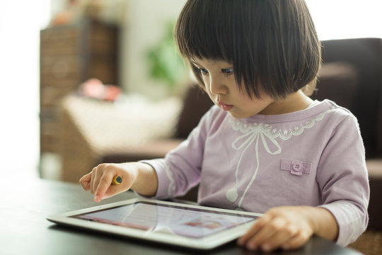 Girl With Black Hair Using Digital Tablet At Home