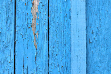 Blue peeling paint on an old wooden barn wall.