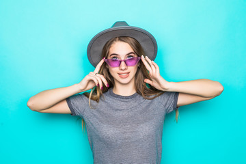 Young woman holding sunglasses and fluppy hat isolated on pastel blue background