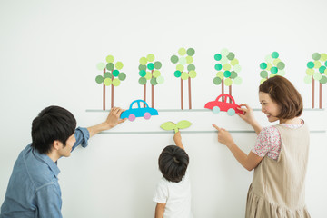 壁のイラストの前の3人家族