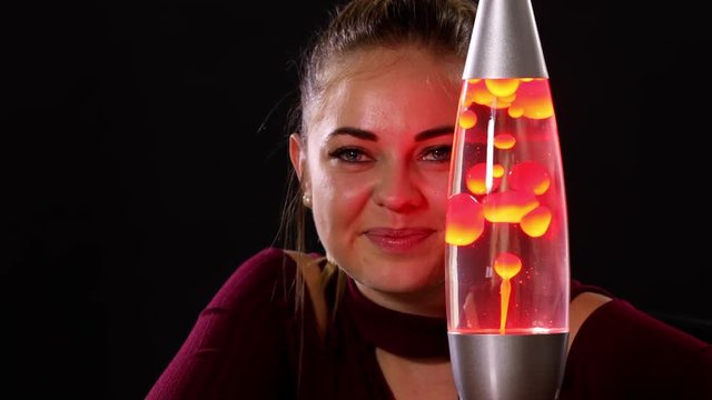 Pretty woman looking at a lava lamp.