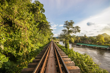 Railway between rocky cliff and river in Kanchanaburi, Thailand