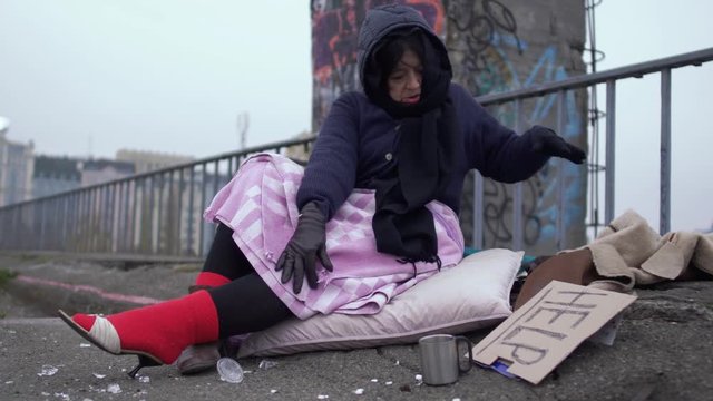 Homeless woman appreciate the shoes worn on a thick red sock and looks at the jacket appreciatively.