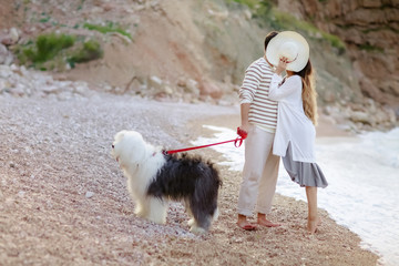 Happy young couple walking with big dog on the beach in summer