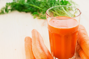 Fresh carrot juice in glass on wooden table background.