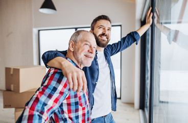 A senior man helping his son with furnishing new house, a new home concept.