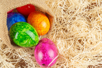 Colorful Easter eggs in Easter basket, straw background
