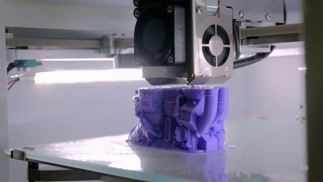 Close up shot - 3D printer prints physical 3D model of purple toy castle with plastic wire filament at modern technology exhibition. Additive technologies, science and futuristic concept