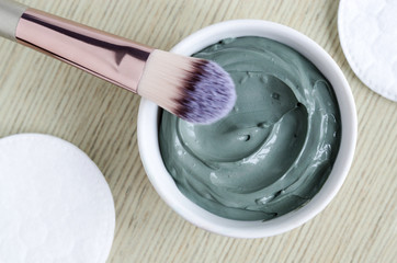 Small white bowl with blue cosmetic clay mask. Homemade beauty treatment. Copy space. 