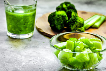 Green vegetable smoothie in glass at gray background