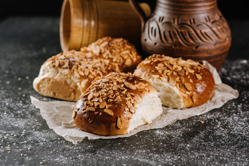 Fresh baked sweet buns with jar and fabric on the black wooden background