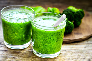 Green vegetable smoothie in glass at wooden background