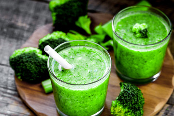 Green vegetable smoothie in glass at wooden background