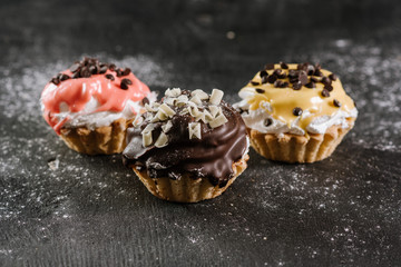Fresh sweet cupcakes on the black wooden background