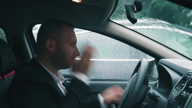 A tired businessman is sitting in the car with his head on the steering wheel, then he slap himself on the cheeks, takes the briefcase and gets out of the car.