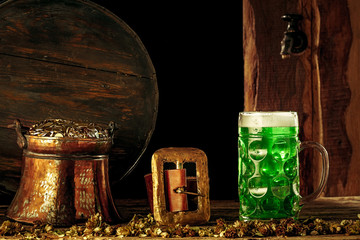 The wooden barrel background with lots of gold coins and a large mug of beer with a green bow. Background for St. Patrick's Day celebration and religious holiday concept