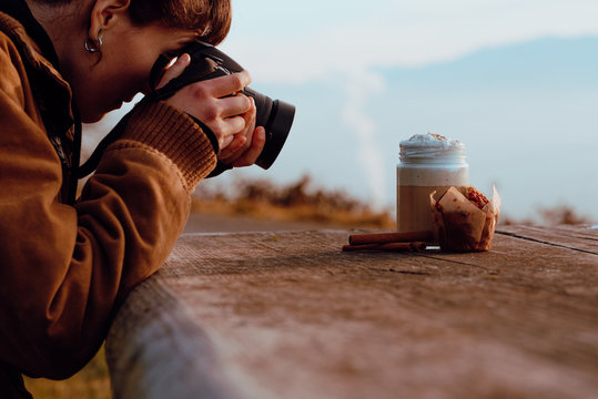 Crop woman taking photos of coffee and cupcake