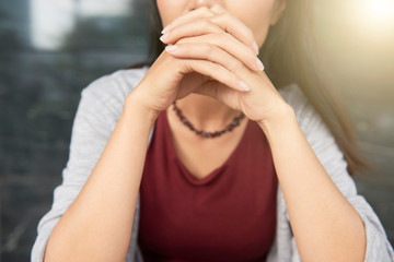 Close-up of woman sitting and holding hands near her mouth, she waiting for somebody or thinking over something