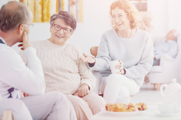 Happy group of elderly people talking and enjoying each other's company at Senior club