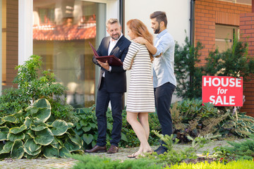 Smiling financial advisor with loan contract talking with house buyers