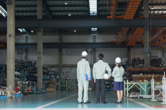 工場で立つ男女作業員の後姿