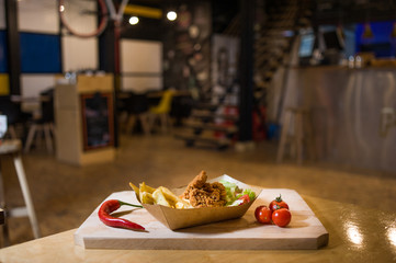Deep fried chicken with fries in a box  with fresh vegetables on a wooden board